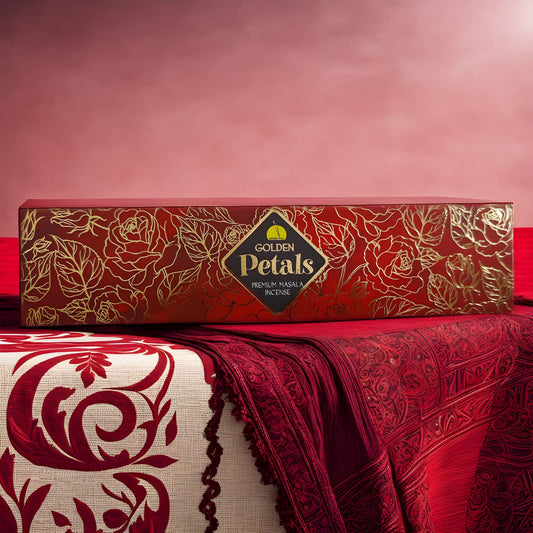 A box of Golden Petals incense sticks by Oriental, displayed on a surface with a red and gold patterned fabric. The box is adorned with a floral design and has the brand name and product title written on it.