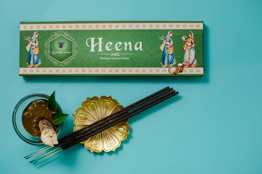 Heena incense sticks with packaging and a small dish on a blue background